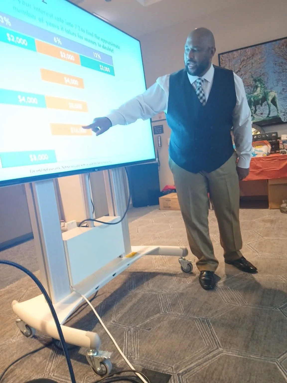 Fred Jordan presenting a financial education lesson beside a large presentation screen